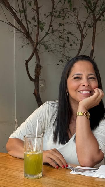 Simone Araujo sorrindo, sentada à mesa